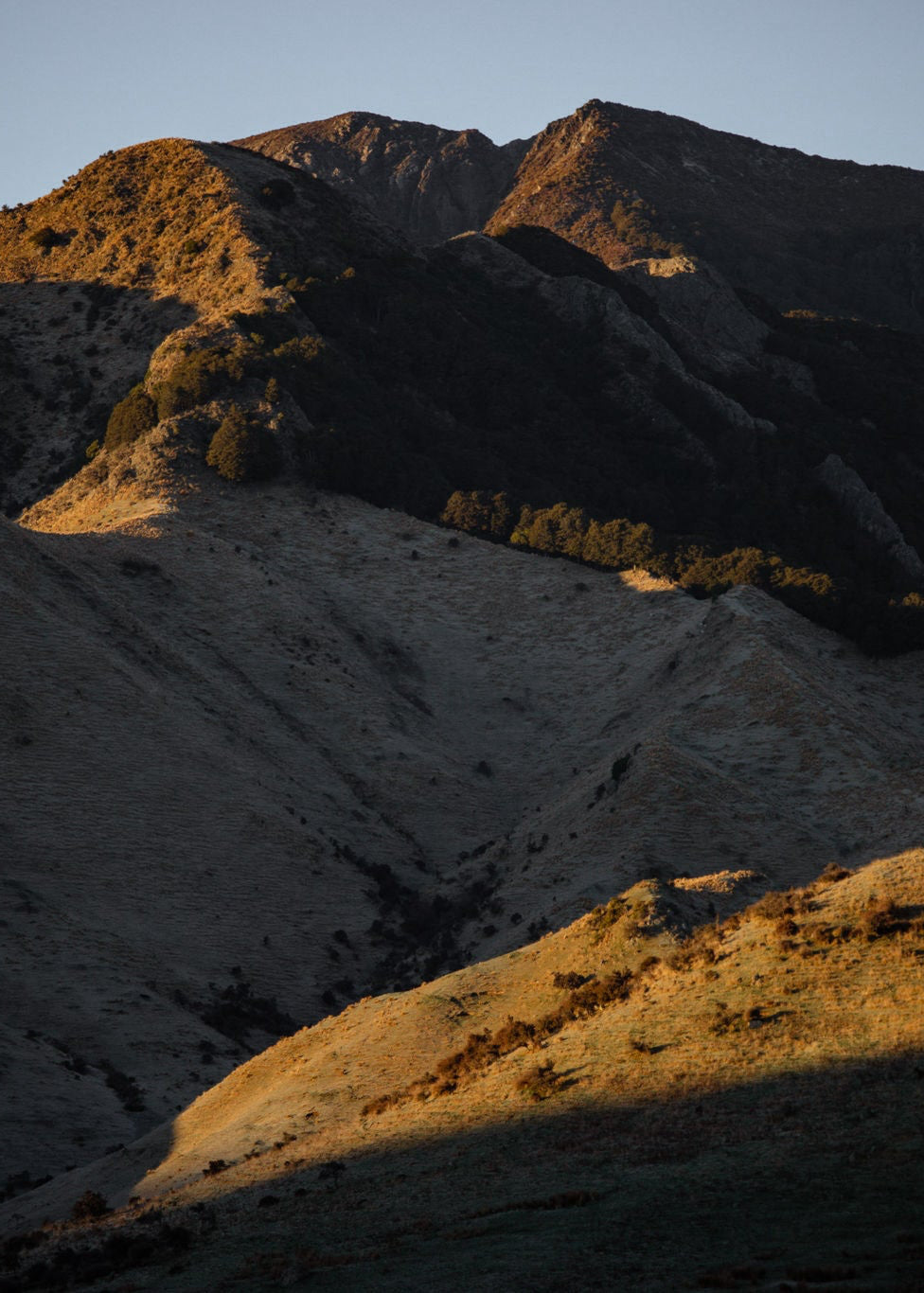 Sunset over a mountain range with shadows casting across the landscape